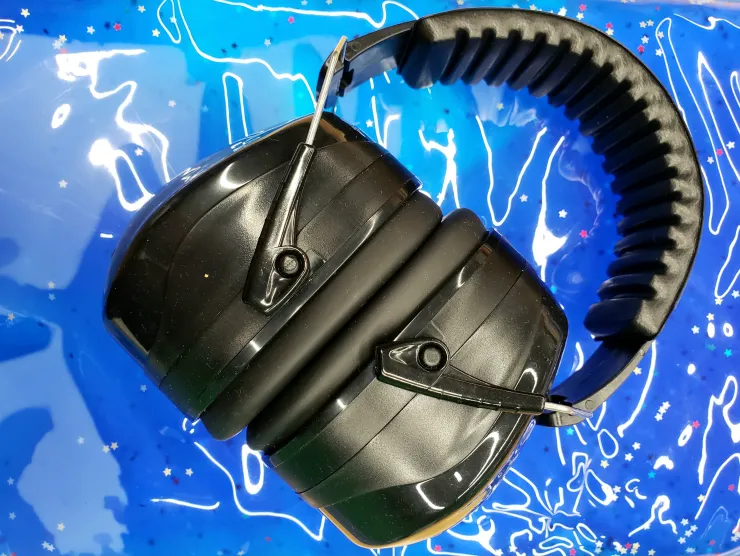 Image of a set of black noise canceling headphones tilted to the right.  The headphones are on a bed of deep blue gel with small stars.  