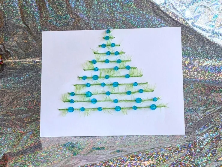Holiday card: a tree made of yarn and beads on cardstock