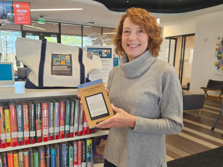 Robbin holds eReader in front of Broader Bookshelf display