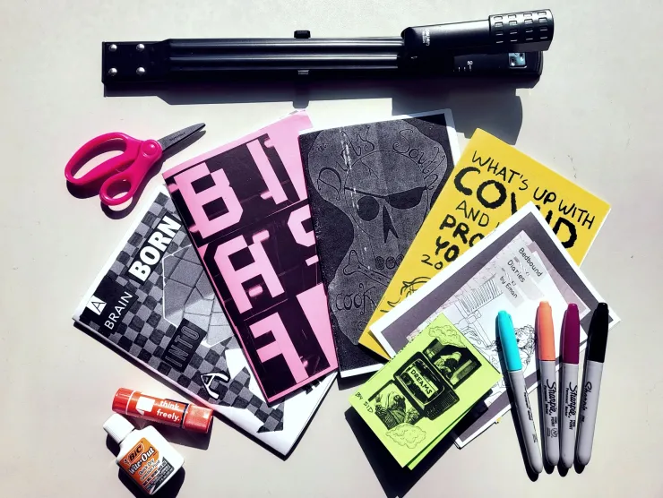 fan of zines with stapler scissors sharpies whiteout and glue stick