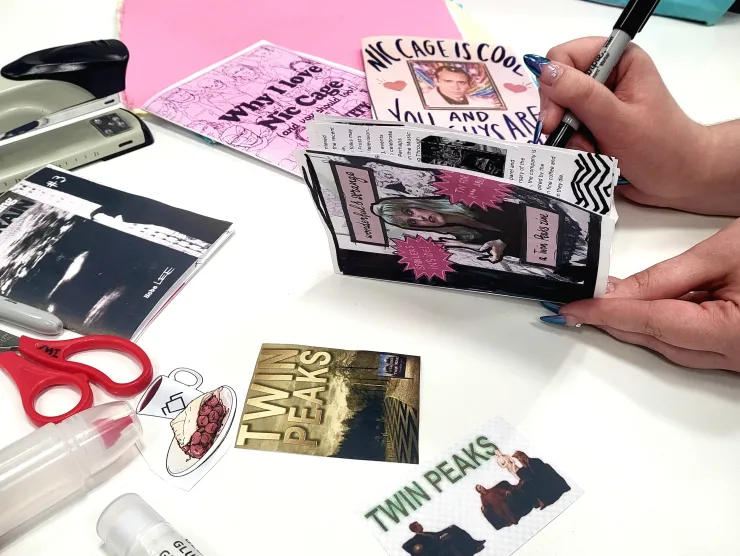 twin peaks fanzine held by a hand with other zines sharpies stapler scissors and glue sticks