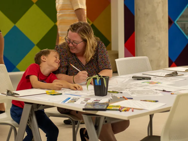 Mother and son sit at table for arts and crafts.
