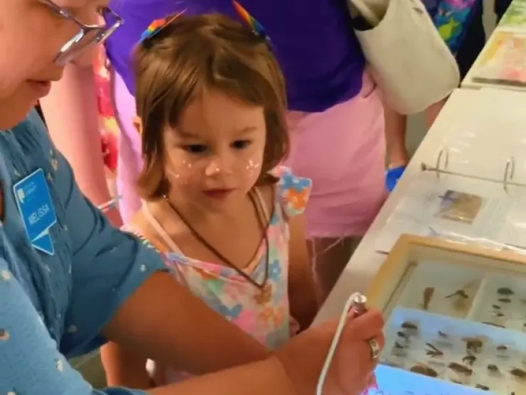 An adult showing a child bugs with a microscope