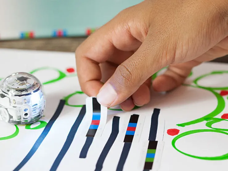 Small round robot with black lines with red, blue, and green strips through it. 