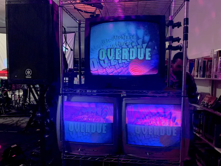 Three CRT televisions with abstract purple and blue visuals, and superimposed text reading "Richland Library Overdue".