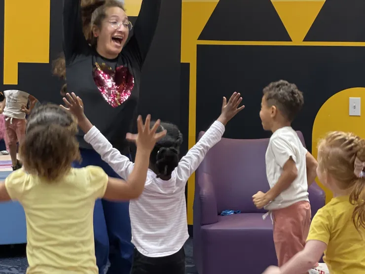 Children jumping in the air with staff during storytime
