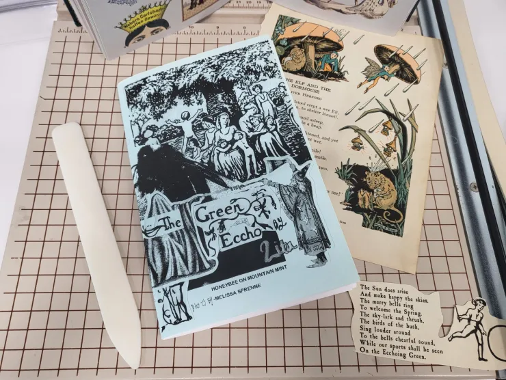 folding bone zine with victorian graphics on blue paper on a grid