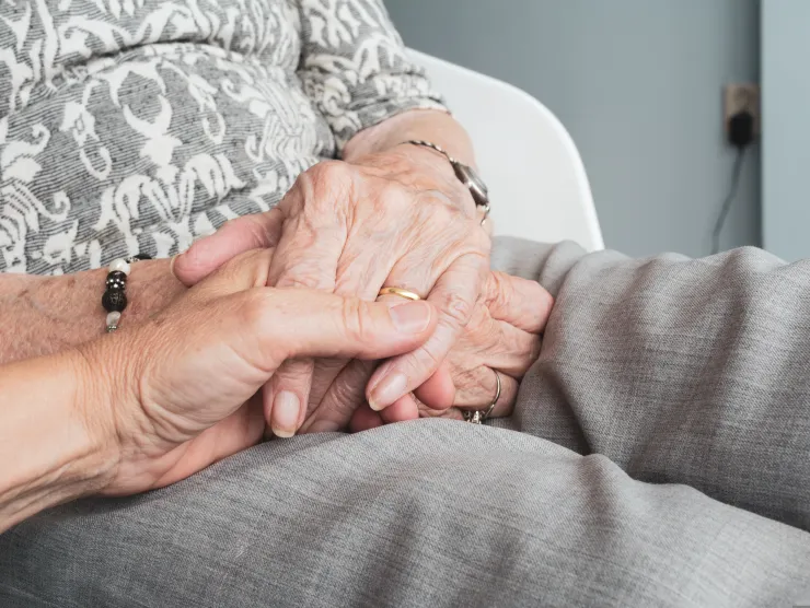 Close up of two individuals holding hands. 
