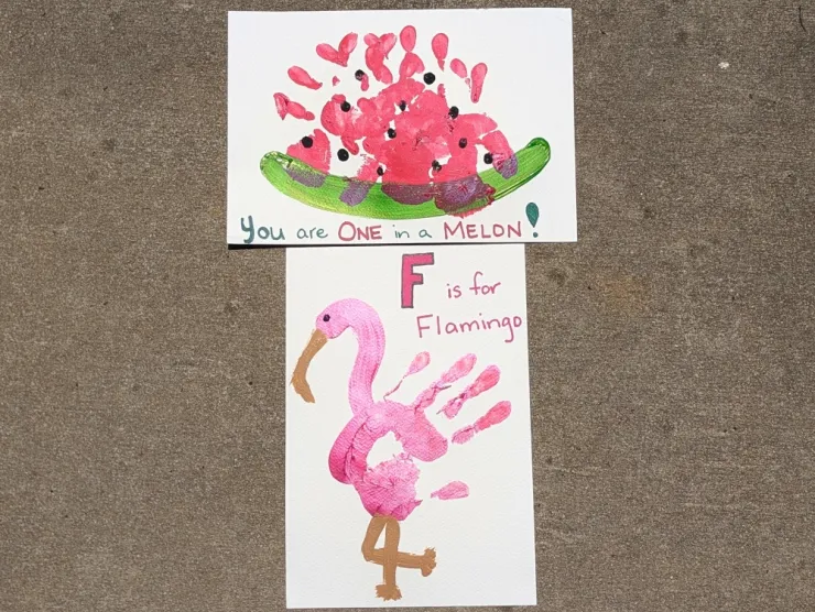 Two paintings: both involve handprints. The top one is a watermelon: a green semi-circle with 4 handprints along the inner curve with black fingerprint dots for seeds and says "You are ONE in a MELON!" The second one is a flamingo: a pink handprint with a neck and head painted on and brown beak and legs that says "F is for FLAMINGO"