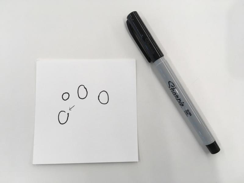 Paper square with four circles drawn haphazardly in black ink.