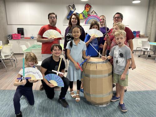 A group of adults and children show off the props they have created.