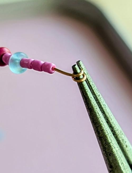 Image of gold wire wrapped in a spiral around one jaw of a pair of round-nose pliers