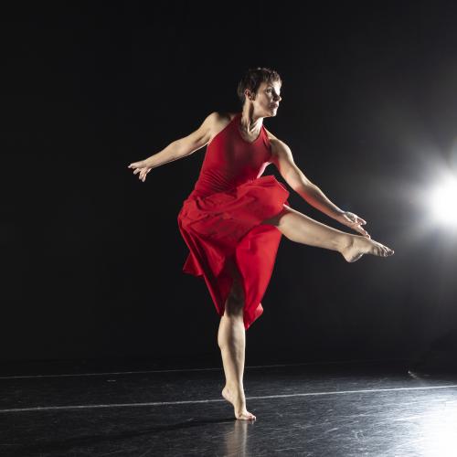 Women in red dress dancing on a stage.
