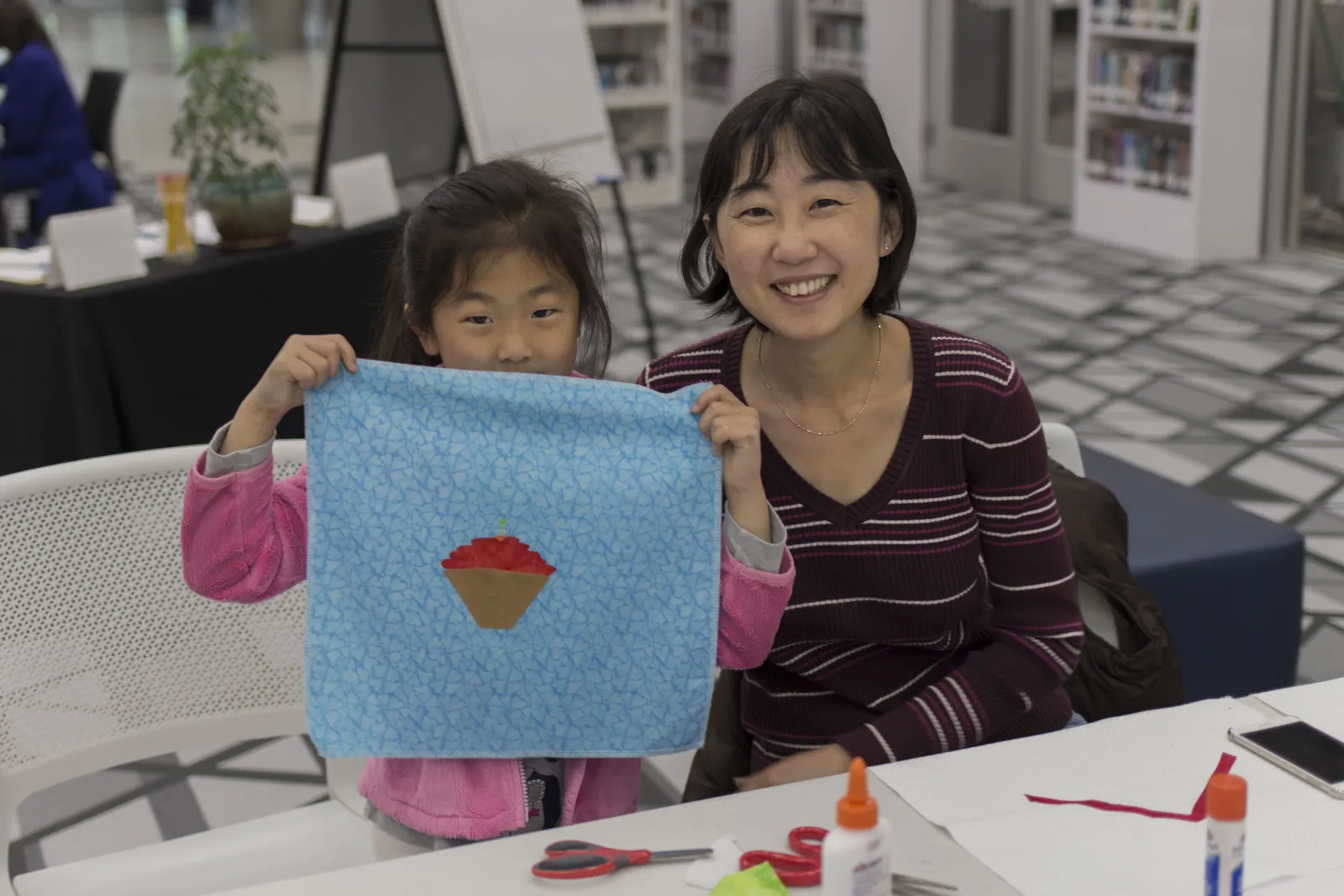 Asian mother and child holding homemade quilt