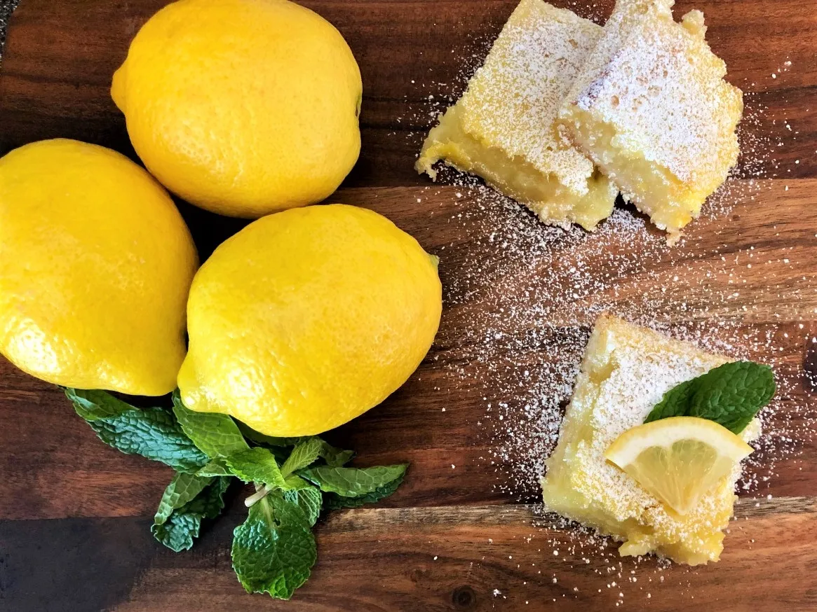 Image of lemons, mint sprigs, and cooked lemon bars dusted with powdered sugar