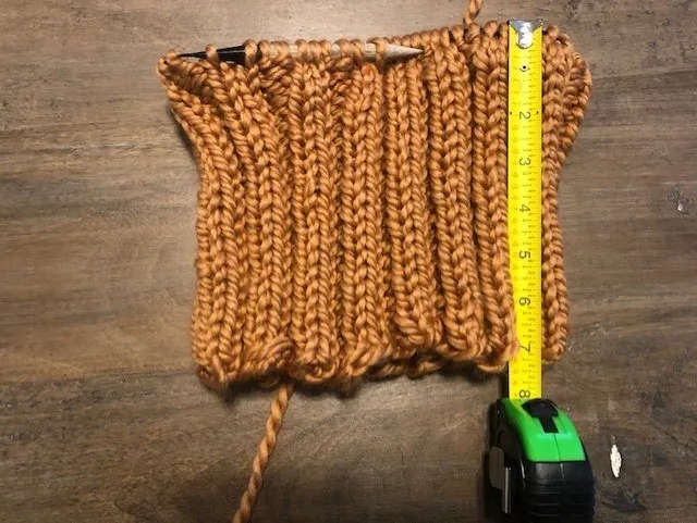 An unfinished knit piece with a 2 by 2 rib and a tape measure showing that it is seven inches long