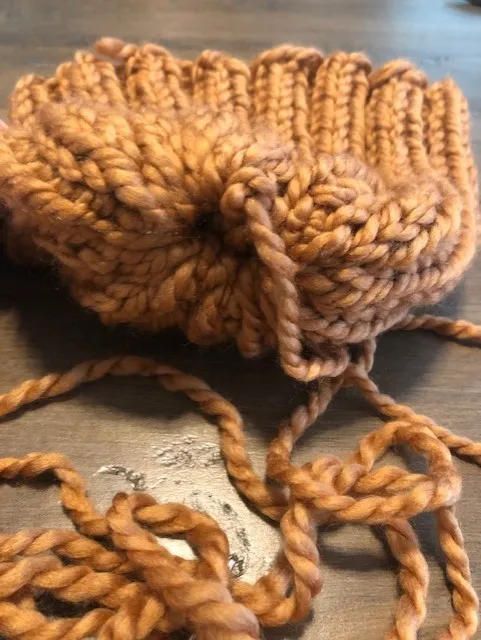 Unfinished piece of knitting showing how one end pulls together 