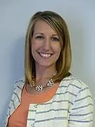Headshot of Jena Martin from Family Connection of SC.  Jena is a white woman with shoulder length blonde hair.  She is smiling and wearing a sparkly necklace, a peach shirt and a grey and white striped jacket.
