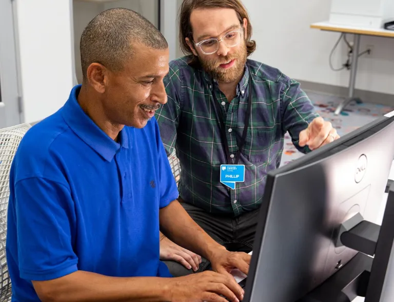 man helping another man at the computer