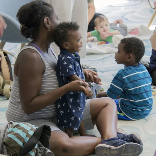 Black woman holds black child on her lap during storytime
