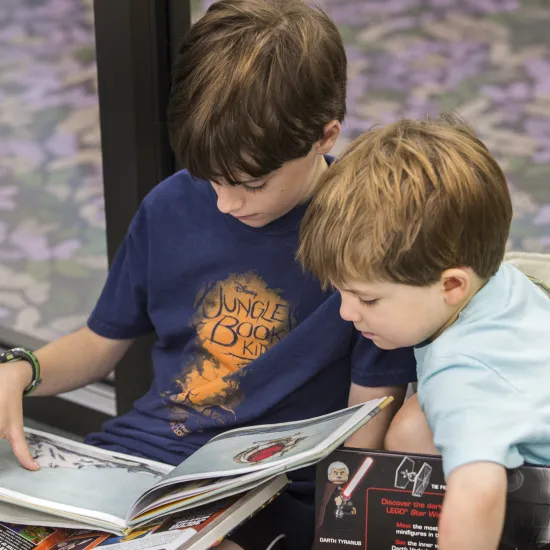 Two white boys sit on the floor and read a book at Richland Library Cooper
