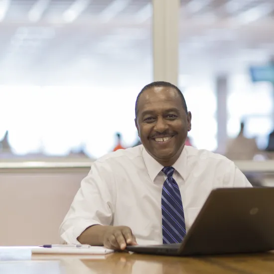 Black male wearing a white shirt and tie sits in front of a lap top computer at Richland Library