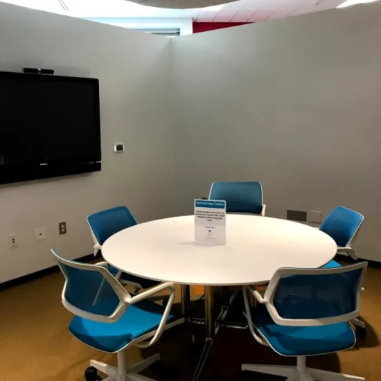 small room with table, 5 chairs and flat panel monitor on wall