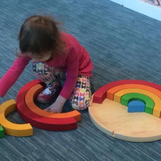 child playing with a wooden rainbow toy