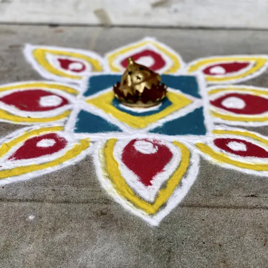 colorful dyed flour arranged in a flower shape on sidewalk, an example of the Indian folk art of Rangoli