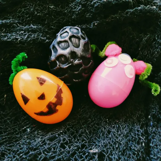 Three plastic eggs decorated to look like a jack-o-lantern, monster and dragon egg
