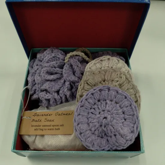 Gift box filled with a crochet bath pouf, three round facial scrubbies, and a bath soak.