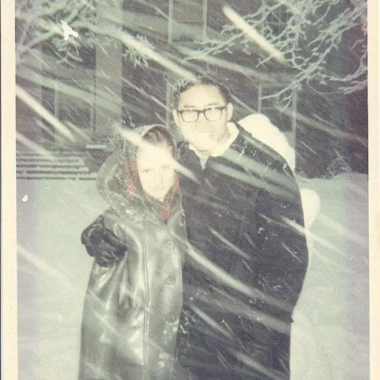 a man and woman hugging each other while snow falls