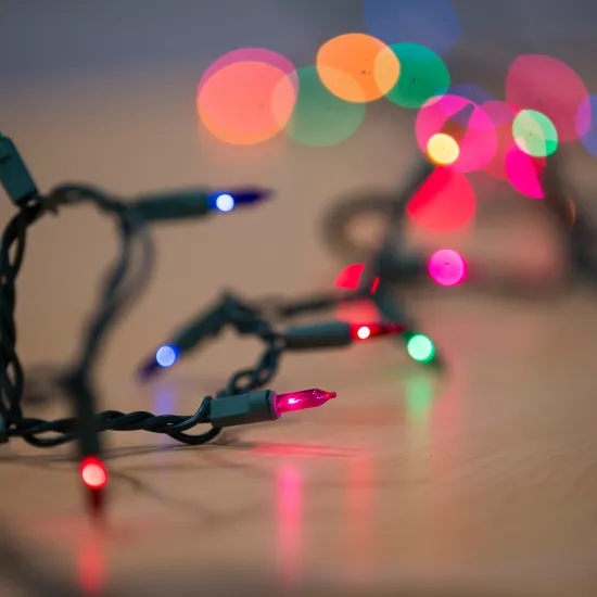 String of multi-colored holiday lights on a wooden table
