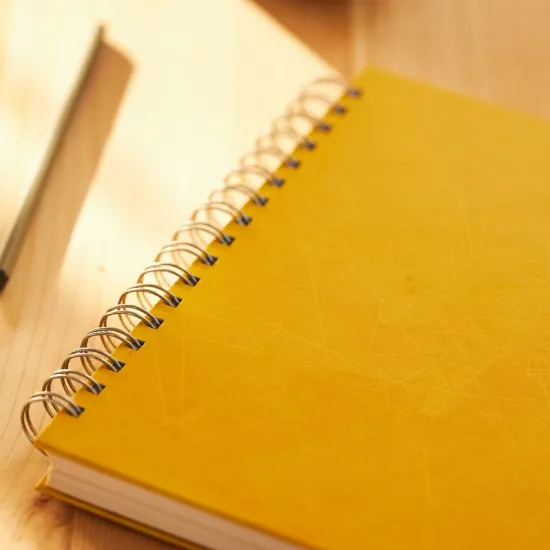 Photo of yellow spiral-bound notebook with pen