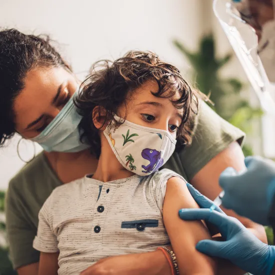 Mother holds child as he prepares for vaccine