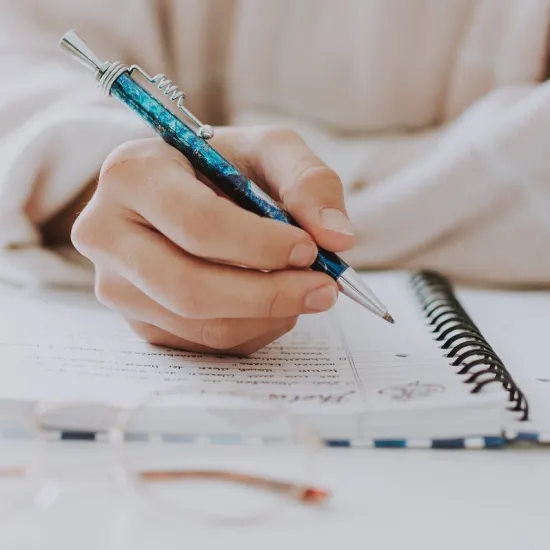 Photo of a hand writing in a spiral bound notebook