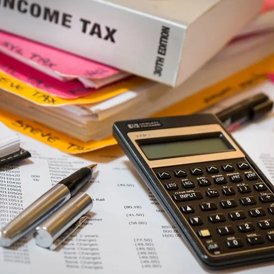 Photo of a calculator and pen with financial papers