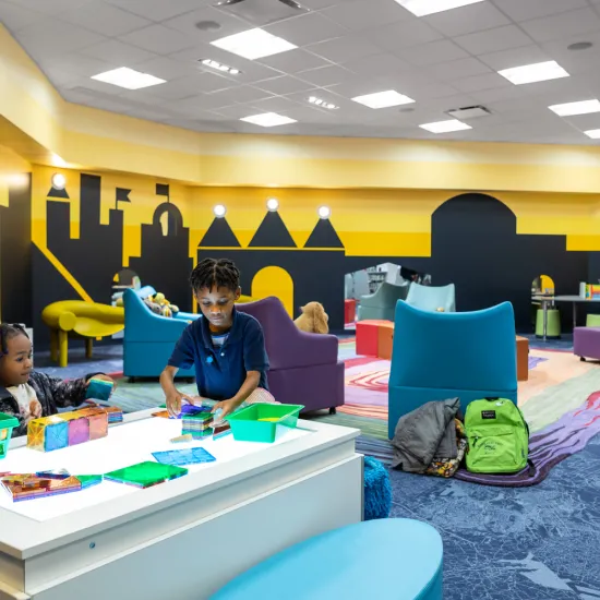 Two children play with magna tiles in the children's area at Northeast
