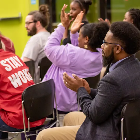 Groiup of adults sitting in chairs face the stage during a performance at the library