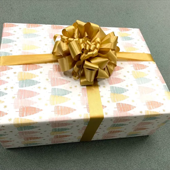 a wrapped present - the gift wrap is covered in small, multicolor trees, and the handmade bow is made of wide gold ribbon