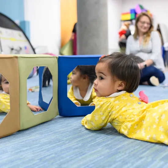 Baby playing on her belly on the floor in library story time room 