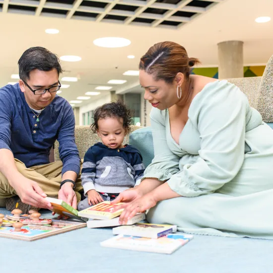 Mom, Dad and baby on the floor looking at books 