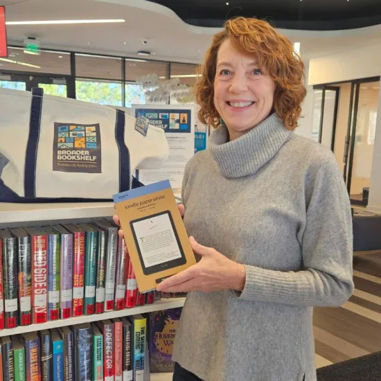 Robbin holds eReader in front of Broader Bookshelf display