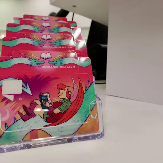 Library card and keychain card depicting Nimona, a character designed by ND Stevenson with the text "A Card with Character"