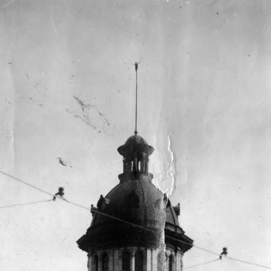 Man stands atop flag pole at State House 1910