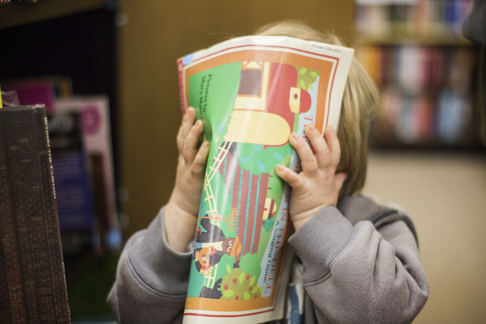Child covering their face with book